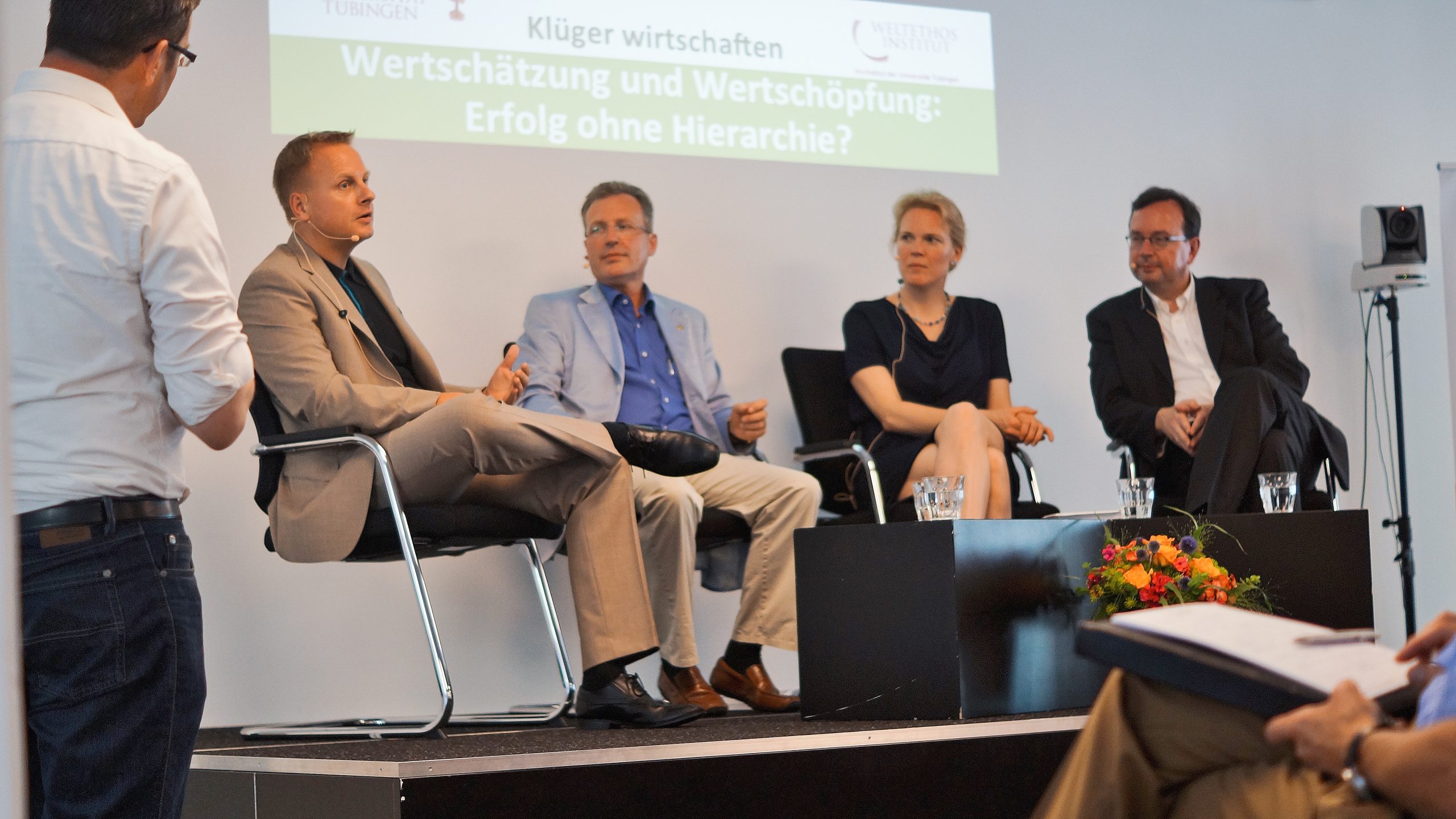 Das Bild zeigt Weltethos Tübingen Gründungsdirektor Claus Dierksmeier mit 3 Gästen bei einer Veranstaltung auf der Bühne sitzend.