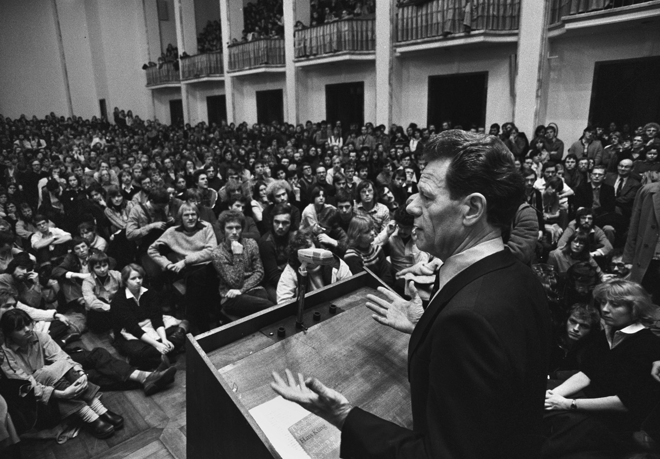 Das Bild (schwarz-weiß) zeigt Hans Küng, den Gründer der Stiftung Weltethos, an einem Pult im vollen Festsaal der Universität Tübingen bei einer Rede.