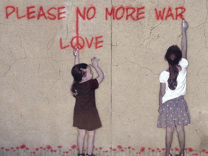 Zwei Mädchen, die "Please no more war" und "love" auf eine Wand schreiben