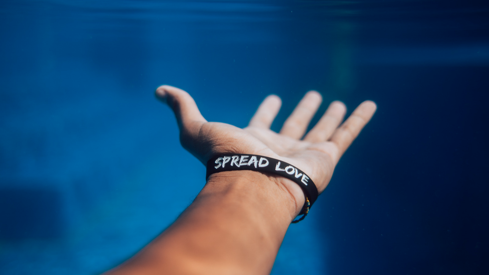 Eine Hand, an dessem Arm ein Armband "Spread Love" steht.