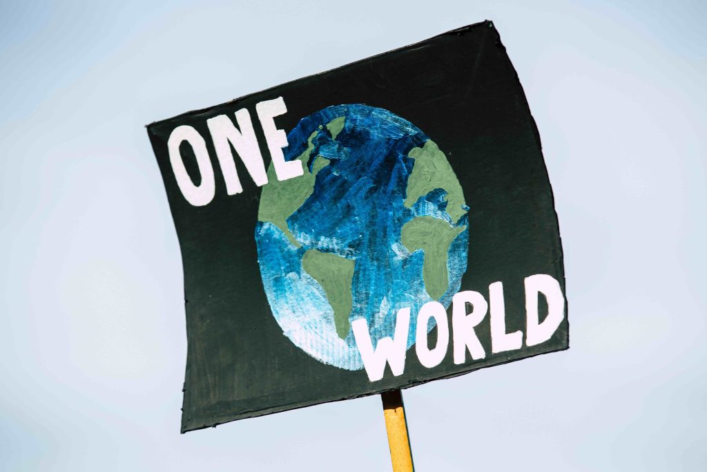 Schild, auf dem ein Bild der Erde mit der Überschrift "One World" steht.