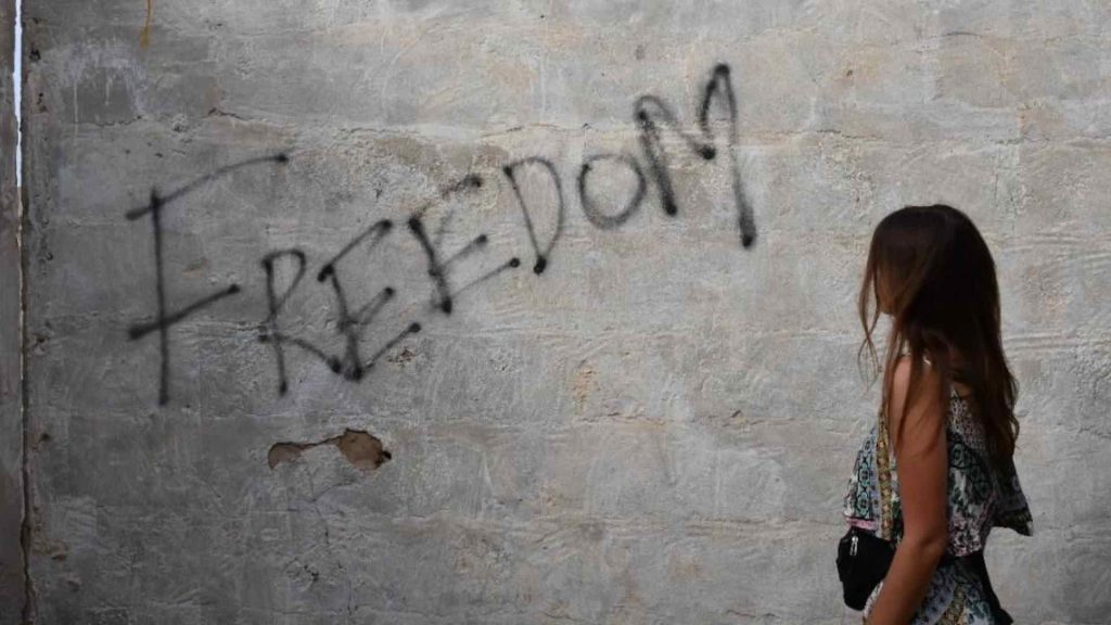 Ein Mädchen schaut auf eine Wand, auf der "Freedom" steht.